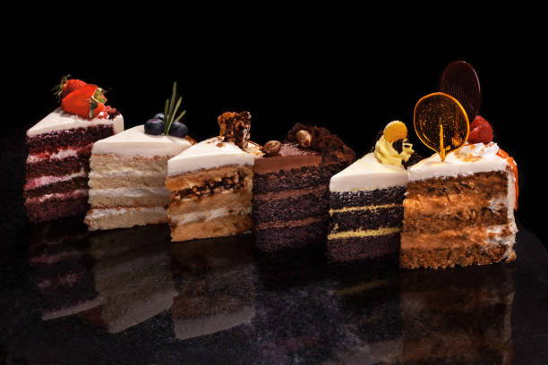 istock Assorted large pieces of different cakes: chocolate, raspberries, strawberries, nuts, blueberries. Pieces of cakes on a black table 975053526