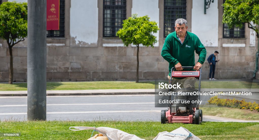 Municipal gardeners mowing the grass in the city center Braga, Portugal - May 23, 2018: Municipal gardeners mowing the grass in the city center on a spring day Gardening Stock Photo