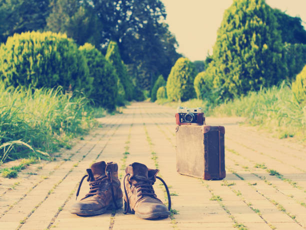 It’s time to wander the world and collect memories. Shabby ankle boots in a foreground. An analog camera on a vintage suitcase, in a blurry background. Nashville effect added.