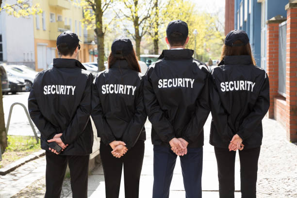 istock Rear View Of Security Guards Standing In A Row 975118158