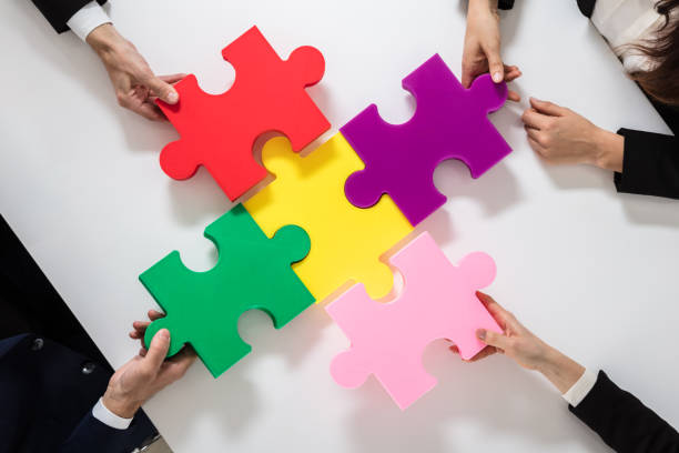 istock Group Of Businesspeople Solving Jigsaw Puzzle 975121408