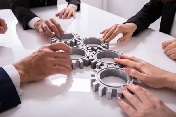 businesspeople joining gears on desk - interlocked imagens e fotografias de stock