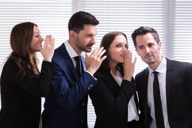 istock Businesspeople Gossiping Into Young Man's Ear 975122784
