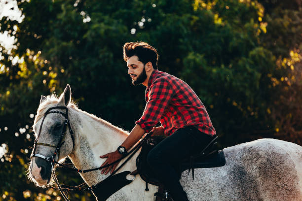istock Young man riding white horse on the countryside 975124932