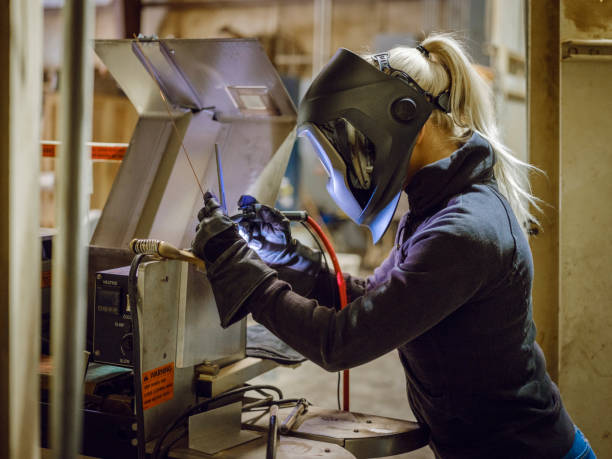 Female TIG Welder A woman tig welder works in a production facility to repair a piece of equipment. tungsten metal stock pictures, royalty-free photos & images