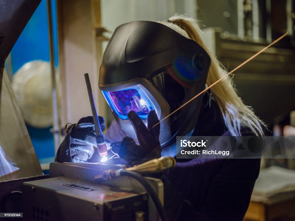 Female TIG Welder A woman tig welder works in a production facility to repair a piece of equipment. Welding Stock Photo