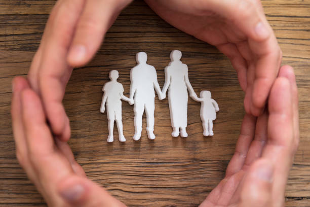 istock Couple's Hand Protecting Family Figures 975126372