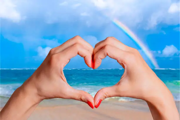 I love the sea concept. Female hands in the shape of heart against the background of the ocean and the rainbow. Dominican Republic.