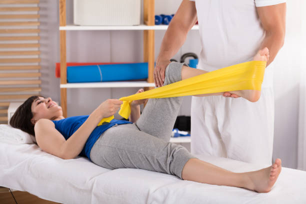 istock Physiotherapist Giving Leg Treatment With Exercise Band 975131696