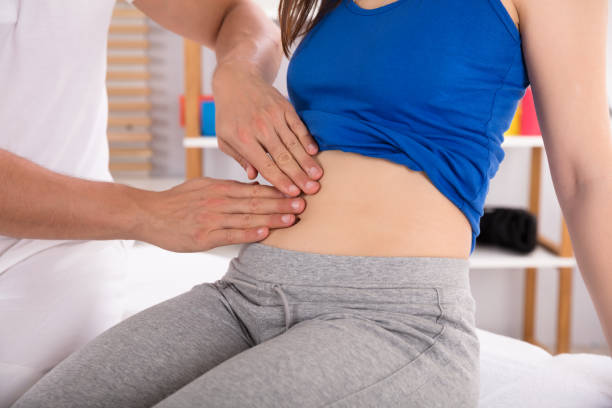 istock Physiotherapist Examining Woman's Stomach 975131764