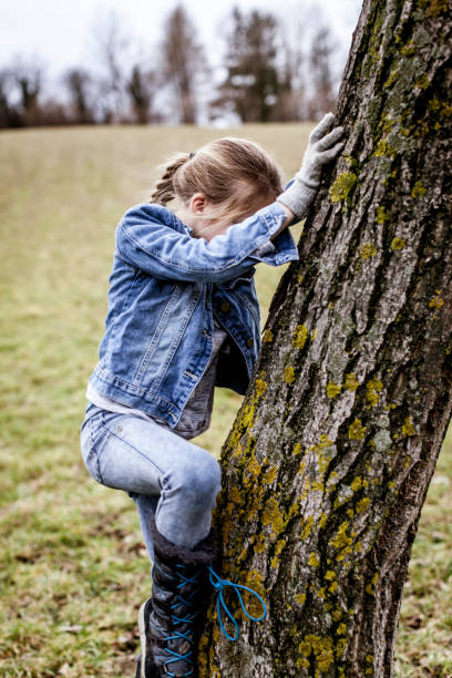 istock Girl Climbing Tree On Field 975133476