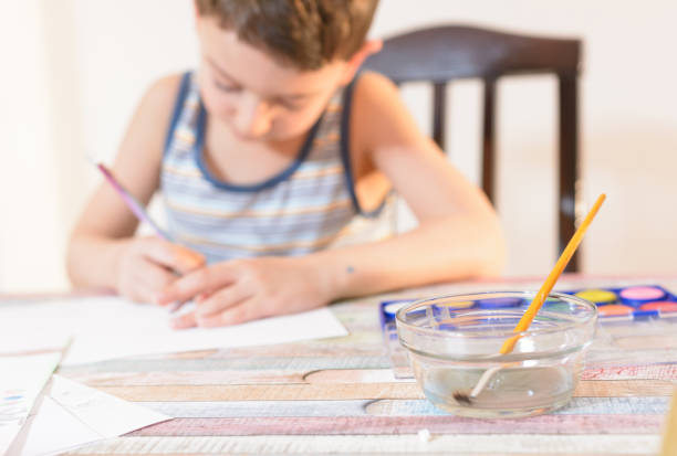 istock Boy is drawing with water color and colorful crayons. 975165884