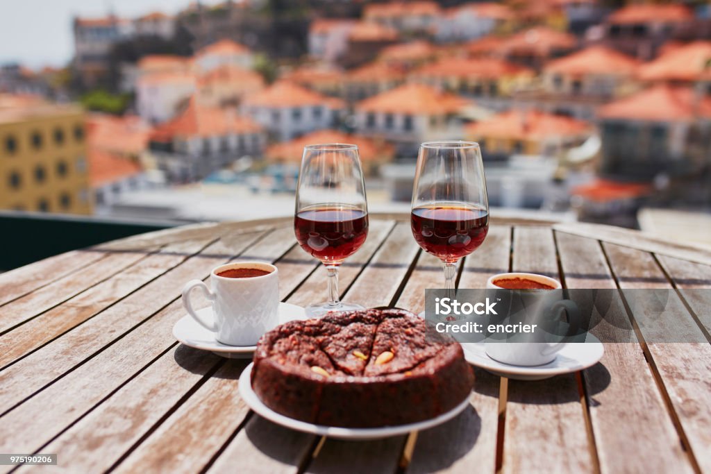 Madeira wine, coffee and hohey cake, View to Funchal, Portugal Two glasses of Madeira wine, two cups of fresh espresso coffee and traditional Portuguese honey and nut dessert bolo de mel in cafe with view to Funchal town, Madeira, Portugal Portugal Stock Photo