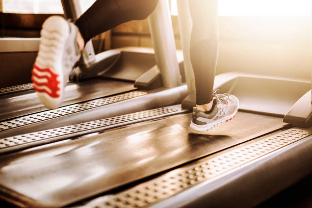 Young athletic man running on treadmill legs close up