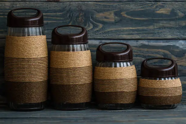 Rope wrapped decorative glass jars on blue wooden background
