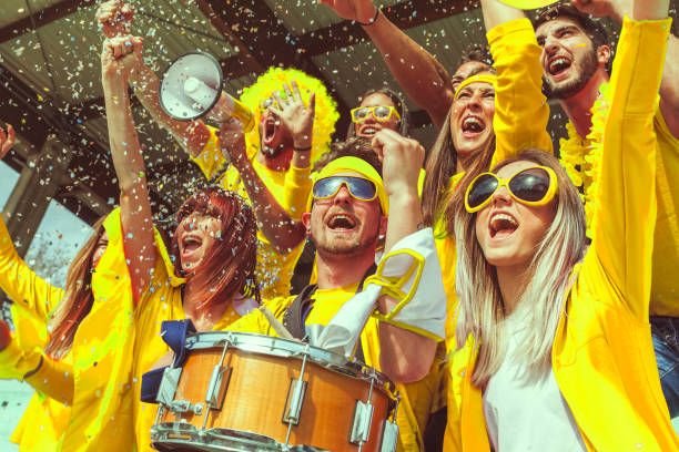 group of fans dressed in yellow color group of fans dressed in yellow color watching a sports event in the stands of a stadium snare drum photos stock pictures, royalty-free photos & images