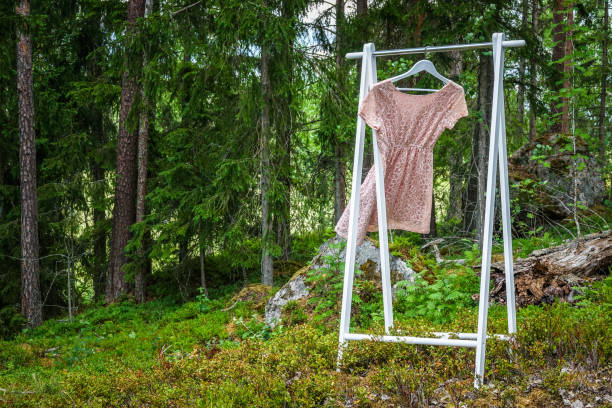 istock Clothes hanger with a pink dress in the forest 975215606