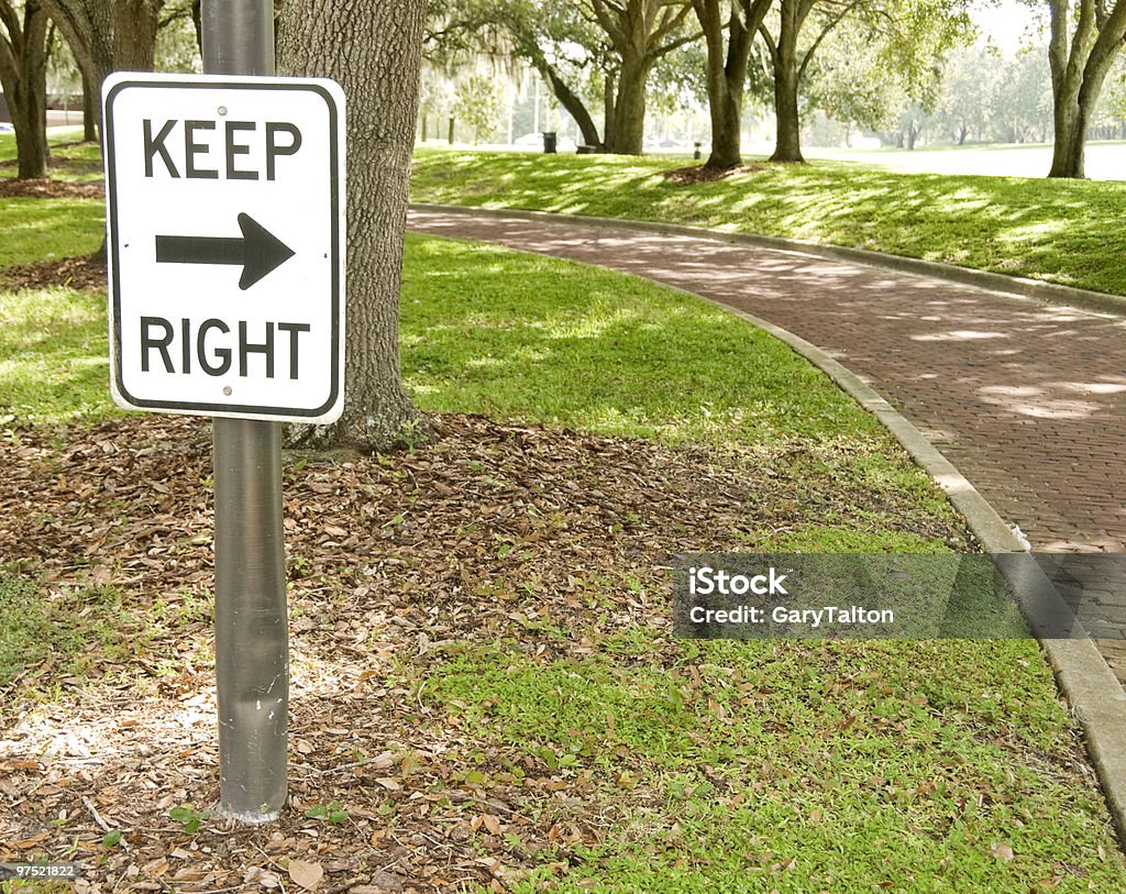 Keep Right Sign Keep right sign pointing in the direction of a shaded brick lined street on a sunny day. Brick Stock Photo