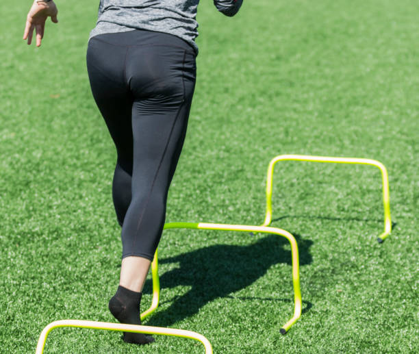 Behind view of female running over mini hurdles