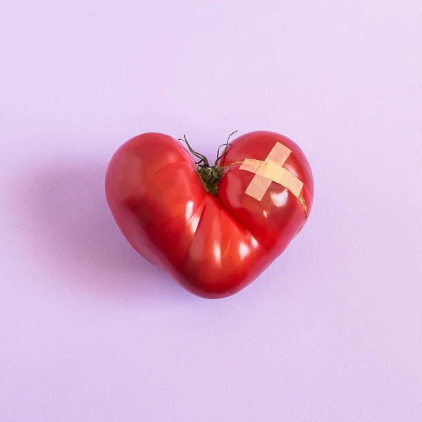 istock Tomato in shape of wounded heart with adhesive plaster 975240040