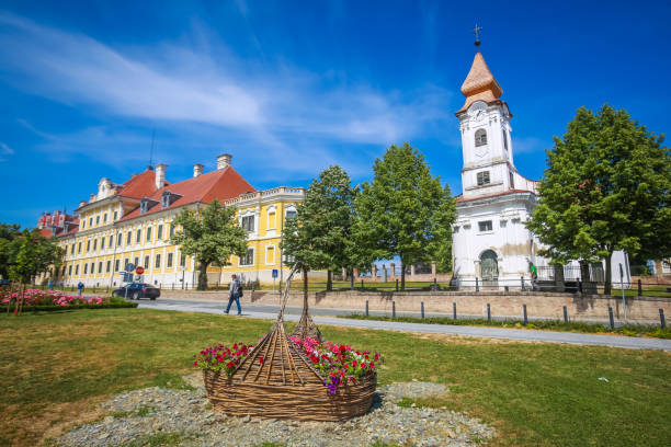 City museum in Vukovar View of a large straw basket with flowers in a park with people walking in the street and the City museum and Chapel of the Saint Roko in the background in Vukovar, Croatia. eltz castle croatia stock pictures, royalty-free photos & images