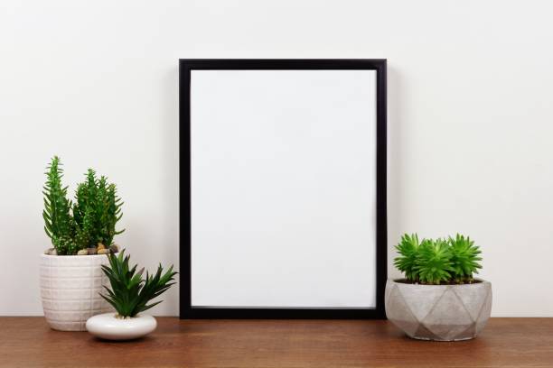 istock Mock up black frame against white wall with succulent plants on a wood shelf 975274356