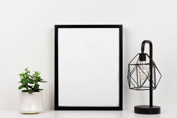 Mock up black frame against white wall with succulent plant and lamp on a white shelf