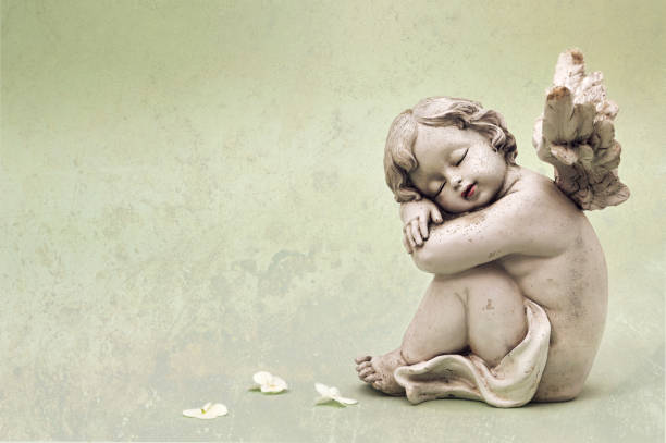Sleeping of little cupid's ceramic doll on stone. Items for house, garden, and interior or exterior installed and cafe decoration.