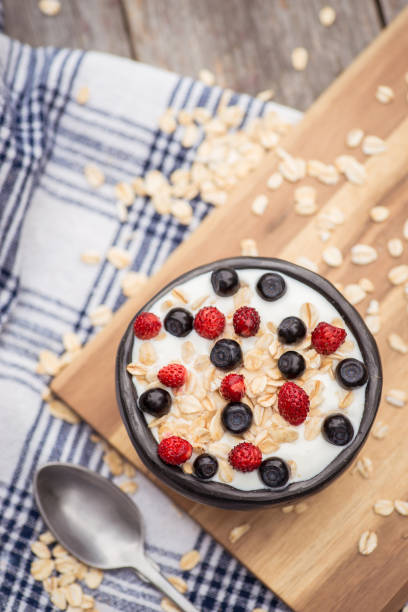 istock Yogurt. Stone bowl with fresh yogurt and berries on rustic table 975315232