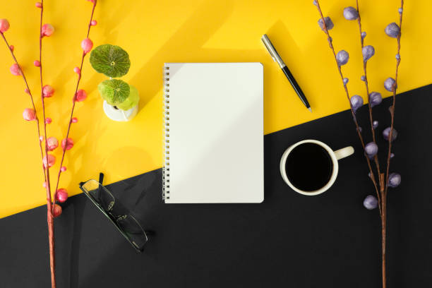 istock Notebook and coffee cup on black and yellow background. 975350500