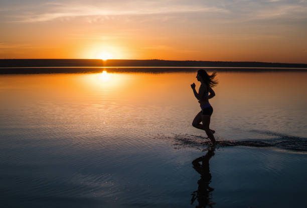 istock Woman Running on the Beach at Sunset 975372218