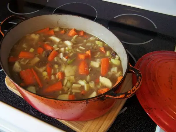 Stew cooked in the Dutch oven pot lifted from the hot oven.