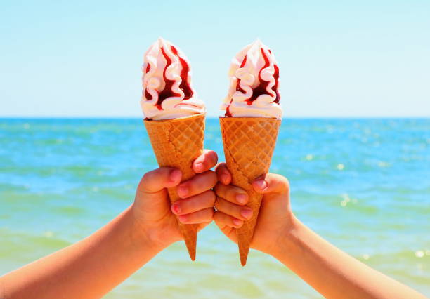 istock Ice cream in children's hands on the beach. 975386674