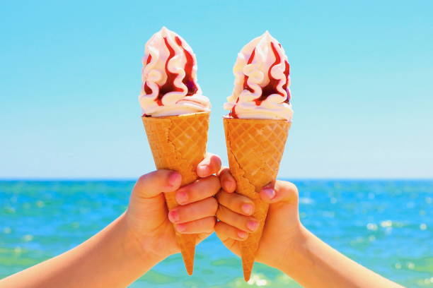 istock Ice cream in children's hands on the beach. 975403692