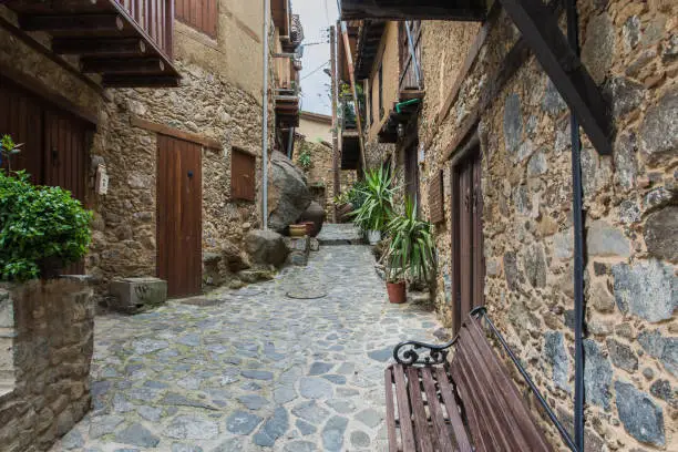 Narrow streets of the old mountain village. Walls of houses made of stone. Cobblestone pavement. Cozy balconies. Pleasant benches for conversation. Troodos Mountains. Cyprus.