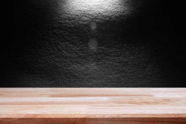 istock empty wooden on black backdrop with spotlight. Wood table top. can used for display or montage your products 975466402