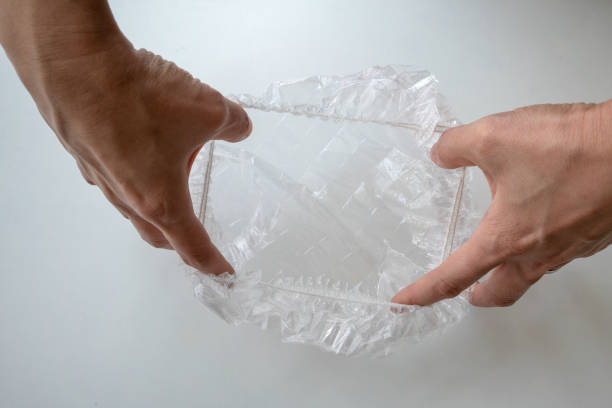 istock Hand expanding disposable shower cap against white background in hotel bathroom. 975489410