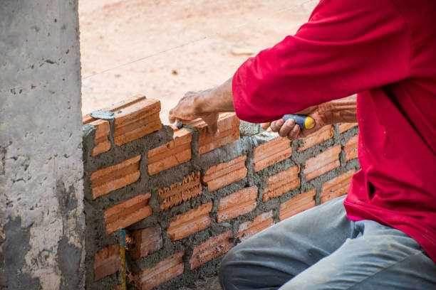 istock Construction worker placing bricks on cement for building exterior walls. 975496878