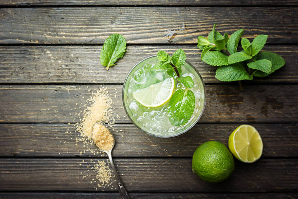 Mojito shot from birds eye view Refreshing mint cocktail mojito with rum and lime, cold drink or beverage with ice on white wooden background, top view mojito stock pictures, royalty-free photos & images
