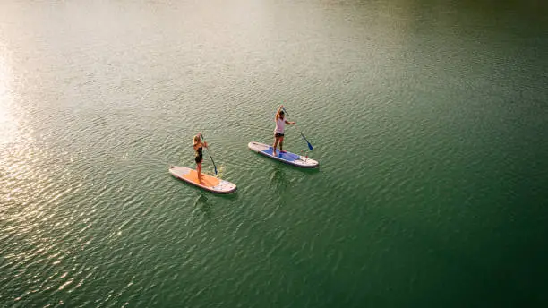 Aerial view of couple paddleboarding on the lake.