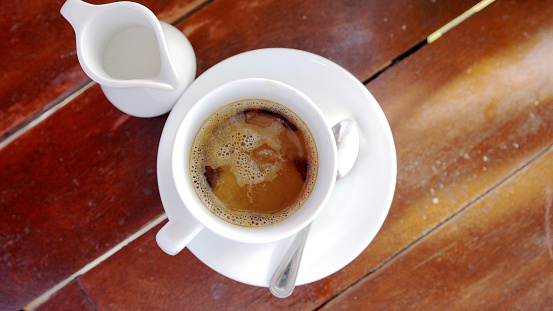 Top view of an espresso coffee in a white coffee cup on a wooden surface.