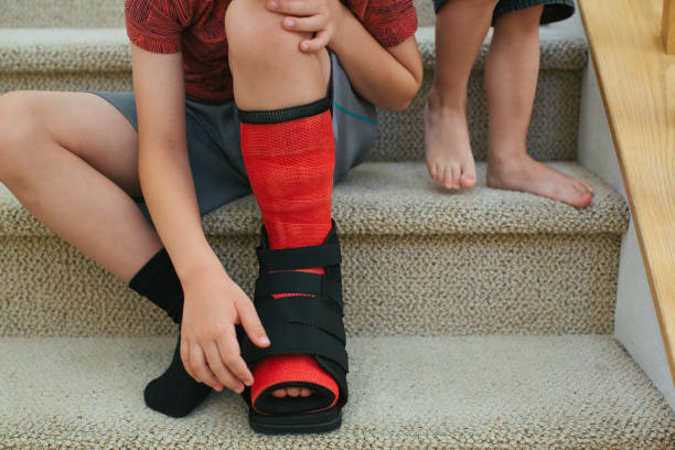 istock Brothers sitting on stairs one with foot cast 975584260