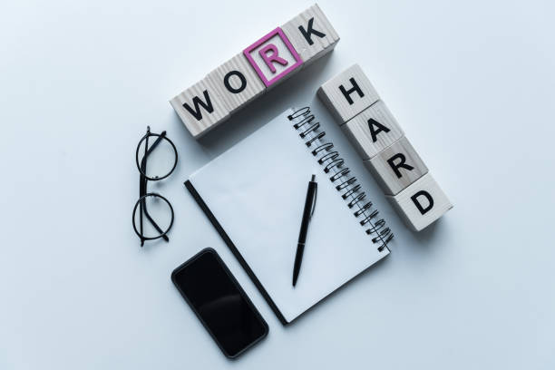 istock overhead view of wooden cubes with words Work Hard and notebook on table 975605462
