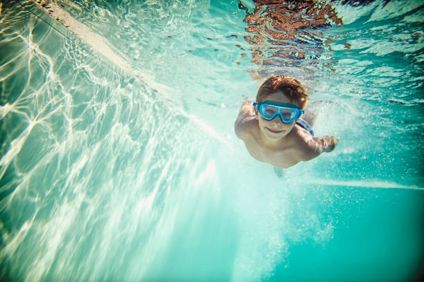 istock Little boy swimming underwater in pool 975612502