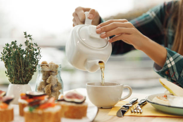 istock close-up partial view of woman pouring tea from teapot during breakfast 975615596