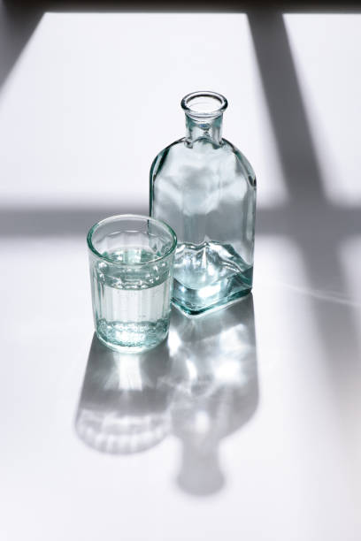 istock close up view of glass and bottle with water on white surface 975620582