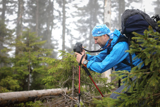 istock Photographer with camera on tripod shooting a landscape in forest 975633150