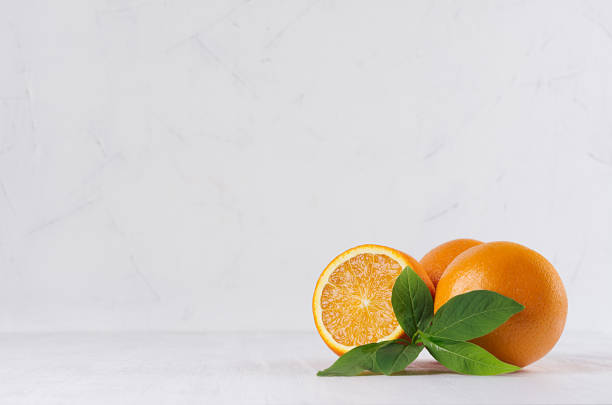 istock Ripe oranges with green young leaves and juice slice on white perspective background. 975637514