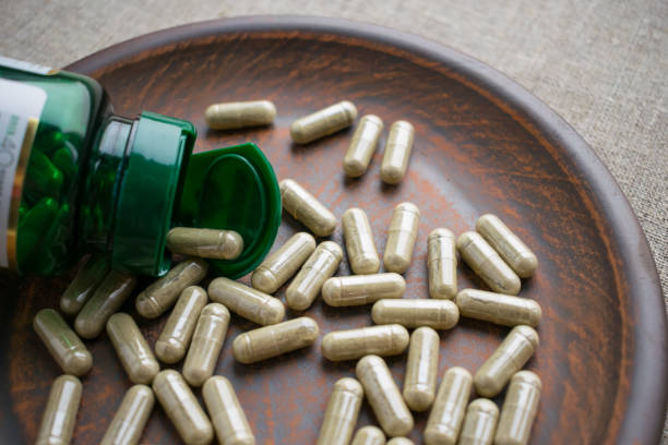 istock Close up biotin capsules and bottle on clay brown plate on burlap background 975647216