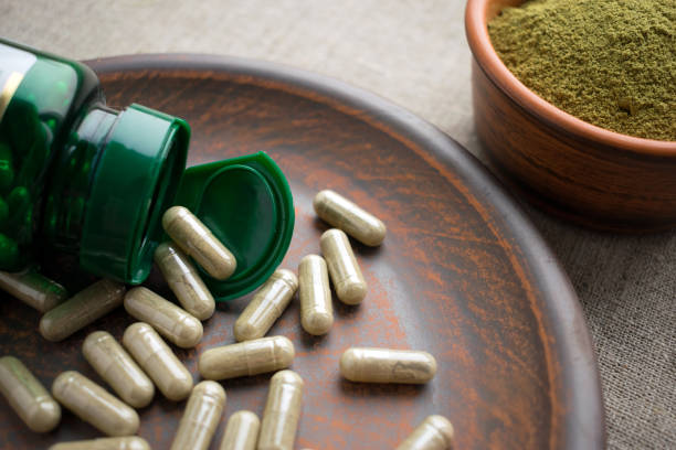 녹색 캡슐, 병 및 삼 베 바탕에 갈색 점토 판에 분말을 닫습니다 - vitamin pill nutritional supplement capsule antioxidant 뉴스 사진 이미지